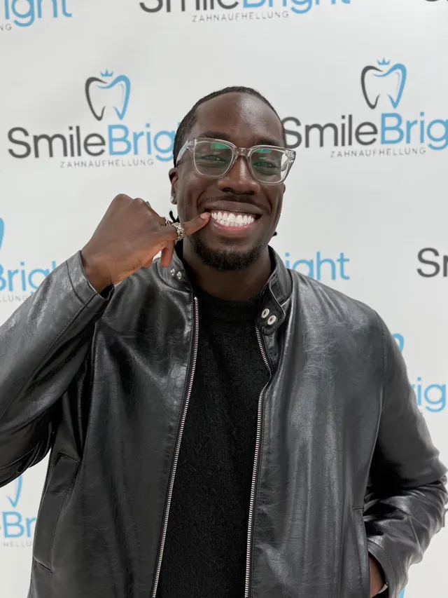 Ein lächelnder Besucher mit Brille vor der Smile Bright Fotowand.
